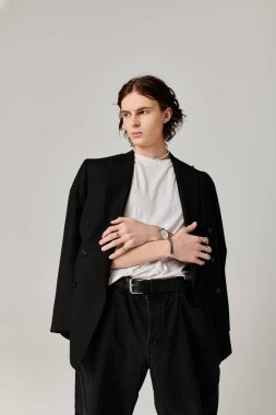 Genç bir adam şık kıyafetini sergiliyor. Spor ceket ve günlük kıyafetler giyiyor. Kendine güveni tam..