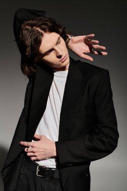 Genç bir adam şık bir elbiseyle şık bir arkaplana karşı güvenle poz verir..