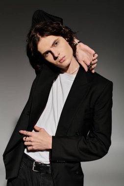 Yakışıklı bir genç, siyah ceket ve beyaz gömlek giyen eşsiz tarzını sergiliyor..