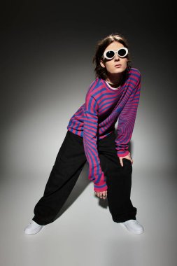 Moda kıyafetleri içindeki büyüleyici genç adam şık bir arka plana eşsiz bir poz verdi..