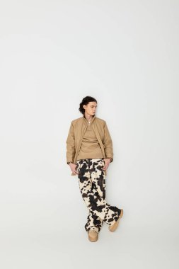 Yakışıklı genç adam zarif bir şekilde duruyor, şık elbisesini duruşuyla ve çekiciliğiyle gösteriyor..