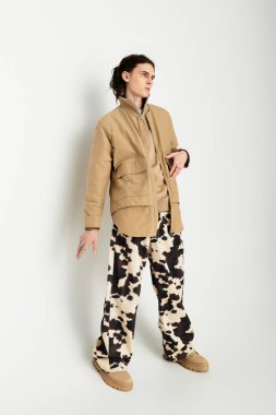 Zarif kıyafetli kendine güvenen genç adam minimalist bir arkaplana karşı duruyor..