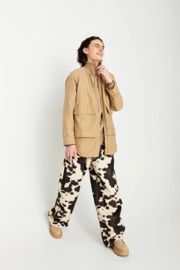 Yakışıklı bir genç adam modaya uygun kıyafetler giyer, konforu ve tarzı neşeli bir ifadeyle harmanlar..