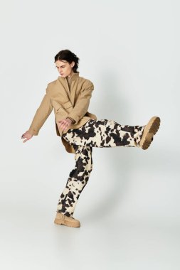 Moda kıyafetli genç adam, yaratıcılığı çağdaş tarzla harmanlayarak dinamik bir poz veriyor..