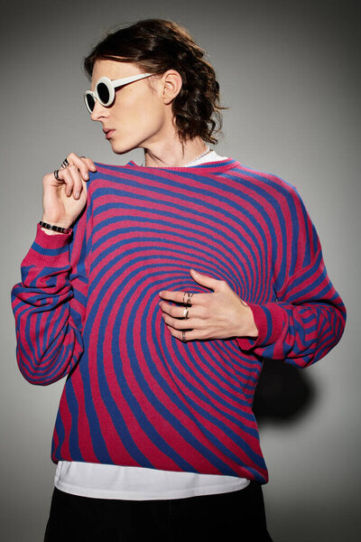 Стильный молодой человек демонстрирует свой талант в ярком свитере и шикарных аксессуарах.