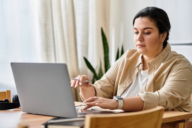 Odaklanmış ve güzel, iri yarı bir kadın, sakin bir atmosferle özenle dizüstü bilgisayarının başında çalışıyor..