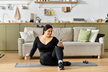 Güzel, iri yarı bir kadın şık evinde spor paspasının üzerinde rahatlar ve spor yapmaya odaklanır..