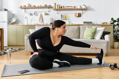 Güzel, iri yarı bir kadın evdeki yoga minderinde esneme egzersizleri yapıyor..