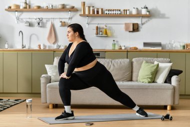 Genç bir kadın parlak, şık bir oturma odasında yoga yapıyor..