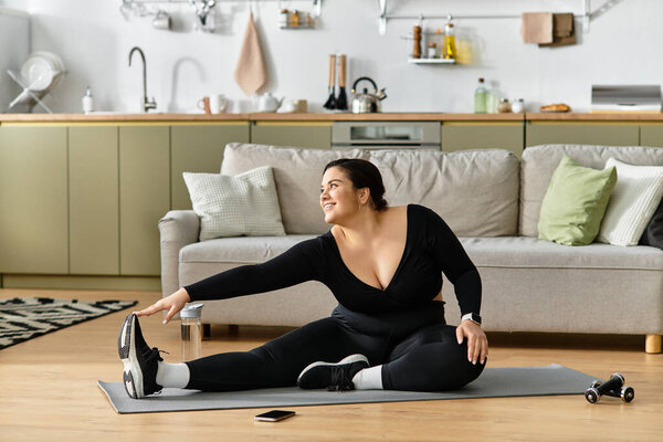 A young plus sized woman confidently stretches on the floor, radiating positivity.