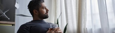 Yakışıklı bir adam bir içkiyle rahatlar, yağmurlu havayı seyrederken yansıtır..