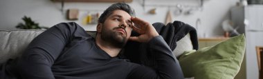 Yakışıklı bir adam, sıcak ve davetkar bir iç mekanla çevrili bir kanepede uzanıyor..