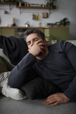 Yakışıklı bir adam, davet ettiği yaşam alanındaki bir kanepede dinlenirken bir anlık sükunetin tadını çıkarır..