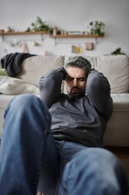 Yakışıklı bir adam rahat bir kanepeye oturur, elleri başının üstünde, derin düşüncelere dalmış..