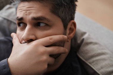 Yakışıklı bir adam, derin düşüncelere dalmış bir kanepede sessizce deneyimlerini gözden geçirir..