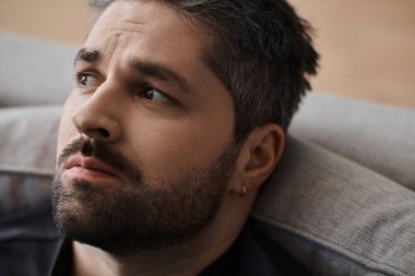 Yakışıklı bir adam düşünceli bir şekilde lüks bir kanepeye oturur ve öğleden sonra güneşinin sıcaklığının tadını çıkarır..
