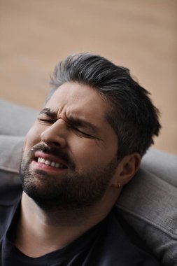 Yakışıklı bir adam düşünceli görünür, yumuşak bir kanepede, sıradan bir kıyafet giyer..