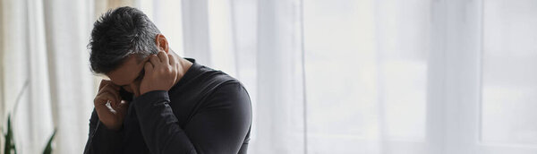 Красивый мужчина с болезненным выражением лица говорит по телефону, казалось бы обеспокоенный новостями.