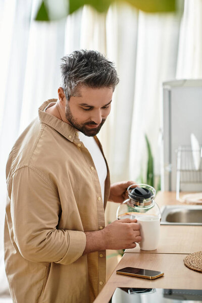 Очаровательный человек готовит свой утренний чай, наслаждаясь спокойной атмосферой кухни.