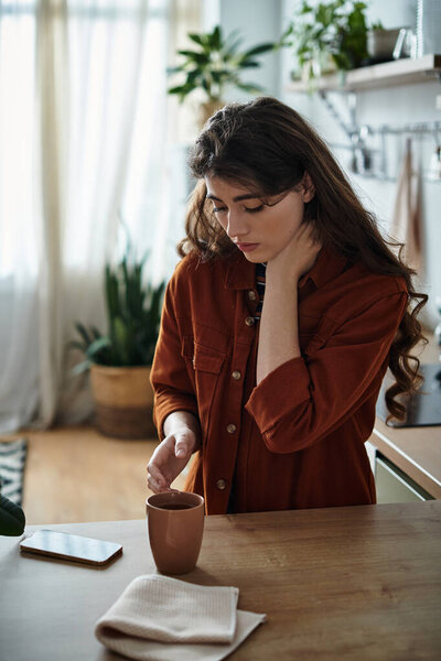 A woman stirs a warm drink in her kitchen, struggling with depression and loneliness.