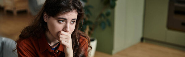 Женщина сидит тихо, потерявшись в мыслях, размышляя о своем внутреннем беспорядке и чувстве печали.