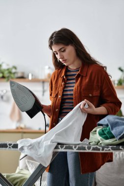 Bir kadın, bitkilerle dolu rahat bir odada giysilerini ütülerken depresyon duygularıyla savaşır..