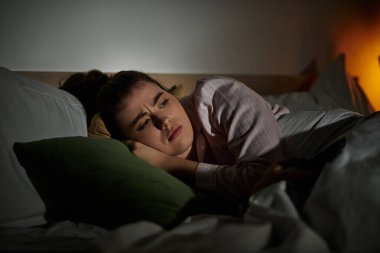 Bir kadın, iç duyguları ve duygularıyla savaşırken derin düşüncelere dalmış, uyanık bir şekilde yatar..