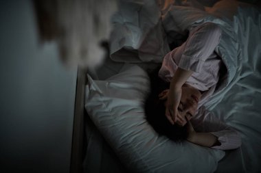 Bir kadın gece çöktüğünde üzüntü ve yalnızlık duygularıyla boğulmuş bir şekilde yatağa uzanır..