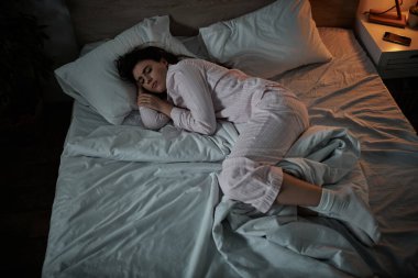 Bir kadın yatağa kıvrılıp yatar, gece çökerken iç karmaşasıyla ve üzüntü duygularıyla savaşır..