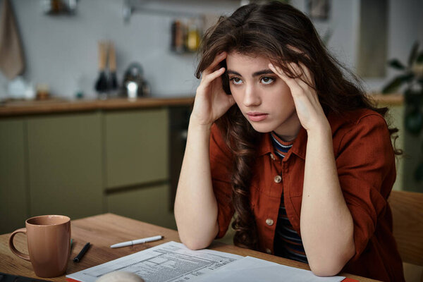 Молодая женщина испытывает глубокие эмоциональные потрясения, сидя за столом со своими мыслями.