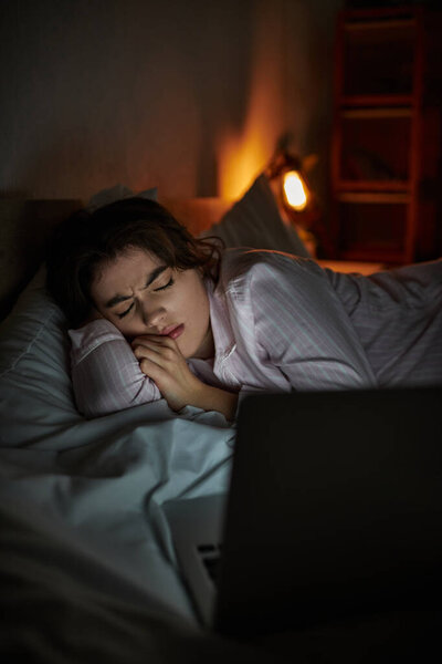 В тускло освещенной комнате женщина лежит в постели, борясь с чувством грусти и изоляции..