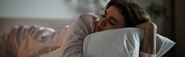 A woman lies in bed, enveloped in her thoughts, feeling the weight of her emotions in solitude.