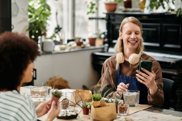 Two friends share laughter while working on their succulent creations in a bright, vibrant workshop.