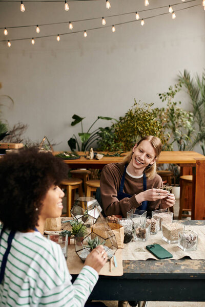 Two friends laughing and crafting unique succulent arrangements in a lively workshop atmosphere.