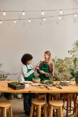 Two friends share laughter and creativity at a lively plant workshop surrounded by succulents. clipart