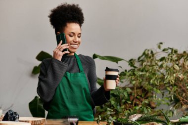Canlı yeşil bir ortamda telefon ve kahveyle neşeli bir kadın..