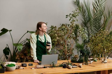 Joyous man working with his laptop in a vibrant green setting. clipart