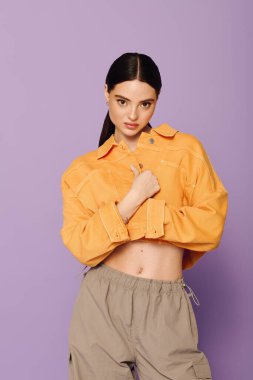 Genç ve modaya uygun bir kadın cesur tarzını turuncu ceketi ve rahat pantolonuyla sergiliyor..