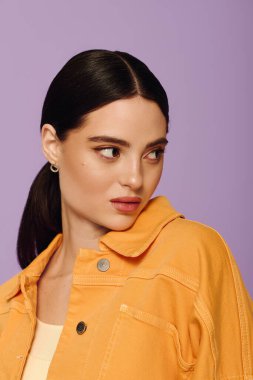 Kendine güvenen genç bir kadın şık sarı ceketini ve çarpıcı özelliklerini vurgulayarak poz veriyor..