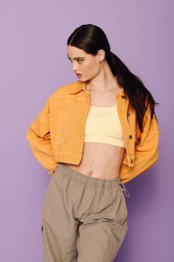 Kendine güvenen genç bir kadın şık ve rahat pantolonlu sarı bir ceket sergiliyor..