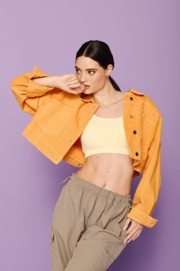 Genç bir kadın kendine güvenerek şık bir elbise içinde büyüleyici bir mor arka plana karşı poz veriyor..