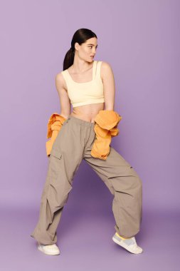 Genç bir kadın modaya uygun giysiler içinde tarzını sergiliyor ve çarpıcı bir şekilde tasasız bir poz veriyor..