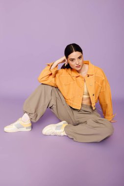 Zarif genç bir kadın şık bir kıyafetle oturarak modanın yaratıcılığını ve tarzını sergiliyor..