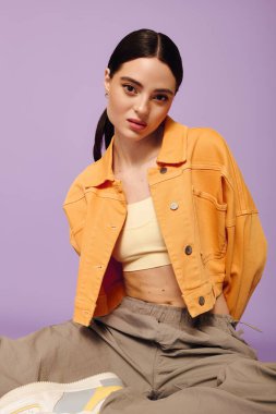 Genç bir kadın moda anlayışını, neşeli pastel bir ortamda moda kıyafetleriyle sergiliyor..