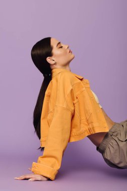 Şık bir genç kadın parlak mor bir arka plana karşı çarpıcı bir şekilde poz verir..