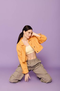 Modaya uygun genç bir kadın dizlerinin üstünde şık bir kıyafetle poz veriyor..