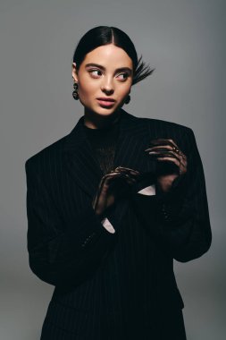 Genç bir kadın dikkat çekici bir kıyafetle moda anlayışını sergiliyor, kendine güvenerek poz veriyor..