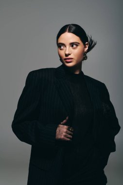 Şık bir genç kadın, moda anlayışını minimalist bir geçmişe karşı çarpıcı bir kıyafetle sergiliyor..