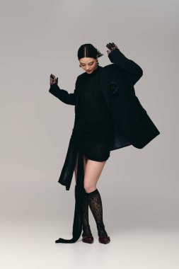 Genç bir kadın şık bir stüdyoda şık bir kıyafet sergilerken kendine güveni tam..