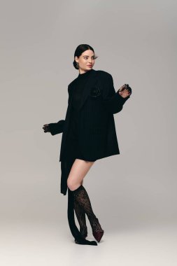 Tarz sahibi genç bir kadın dikkat çekici bir siyah elbise sergiliyor..
